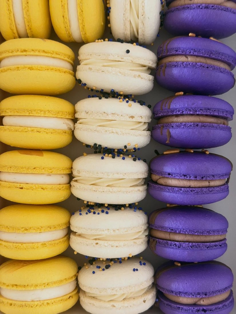 Rows of yellow, white, and purple macarons in school colors