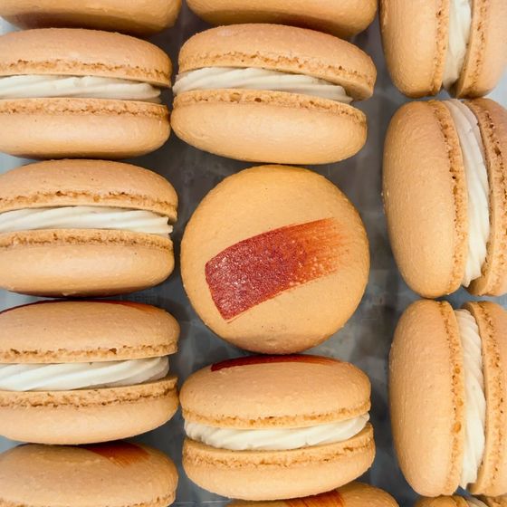 A box of peach-colored apple maple bacon macarons